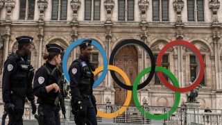 A woman walks past Paris' City Hall where the five-Olympic rings are on diplay, on October 26, 2017, after the city was awarded the 2024 Olympics Games. / AFP PHOTO / CHRISTOPHE SIMON FRANCE-OLY-2024-PARIS