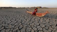 Children stand on a boat lying on the dried-up bed of Iraq's receding southern marshes of Chibayish in Dhi Qar province, on July 24, 2022. - The reputed home of the biblical Garden of Eden, Iraq's swamplands have been battered by three years of drought and low rainfall, as well as reduced river flows from neighbouring Turkey and Iran. Vast expanses of the Huwaizah Marshes, which straddle Iraq's border with Iran, and the touristic Chibayish Marshes, have now become cracked ground, smattered with yellowing shrubs. (Photo by Asaad NIAZI / AFP)