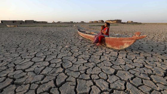 Children stand on a boat lying on the dried-up bed of Iraq's receding southern marshes of Chibayish in Dhi Qar province, on July 24, 2022. - The reputed home of the biblical Garden of Eden, Iraq's swamplands have been battered by three years of drought and low rainfall, as well as reduced river flows from neighbouring Turkey and Iran. Vast expanses of the Huwaizah Marshes, which straddle Iraq's border with Iran, and the touristic Chibayish Marshes, have now become cracked ground, smattered with yellowing shrubs. (Photo by Asaad NIAZI / AFP)